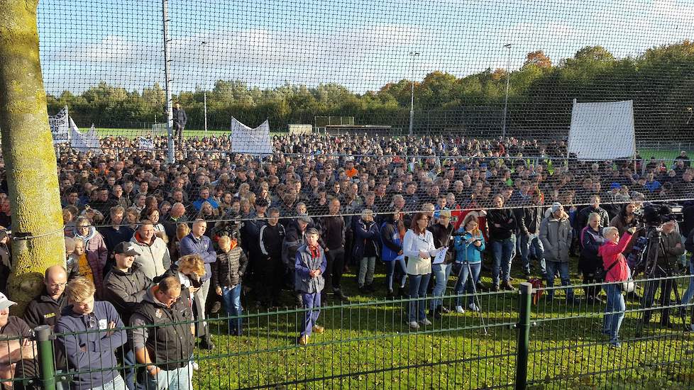 Boeren luisteren vanaf een sportveld naar de toespraken op het podium in Bilthoven.