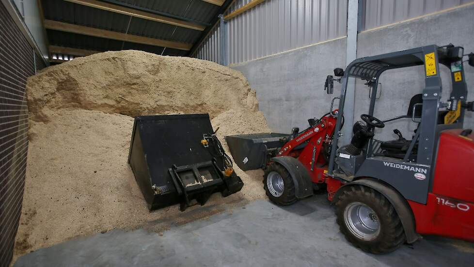 Met een shovel en een zaagseldoseerbak worden de varkenshokken drie keer per week ingestrooid.