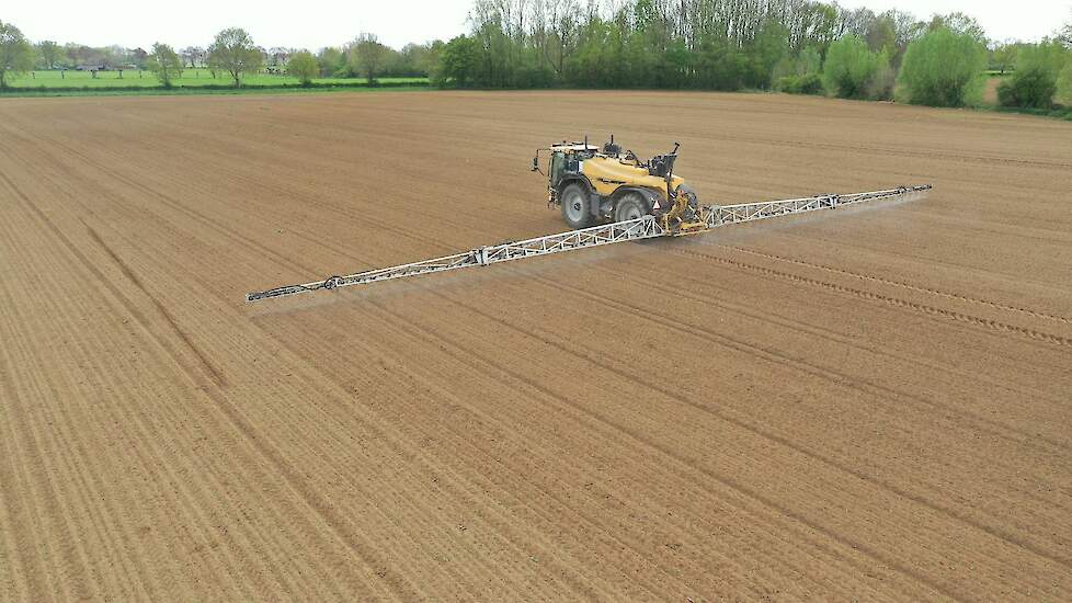 spuitmachine brengt gewasbeschermingsmiddel op akker vlakbij natuur