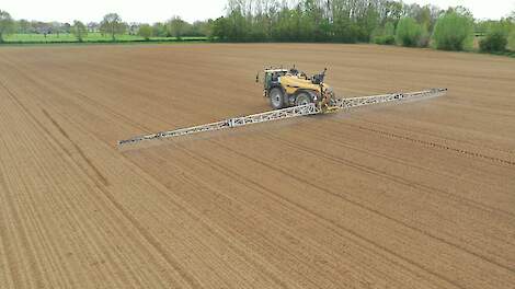 spuitmachine brengt gewasbeschermingsmiddel op akker vlakbij natuur